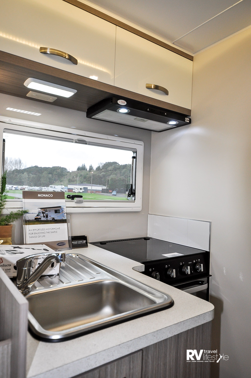 The L-shaped galley area is compact with storage lockers overhead, drawers and cupboards below
